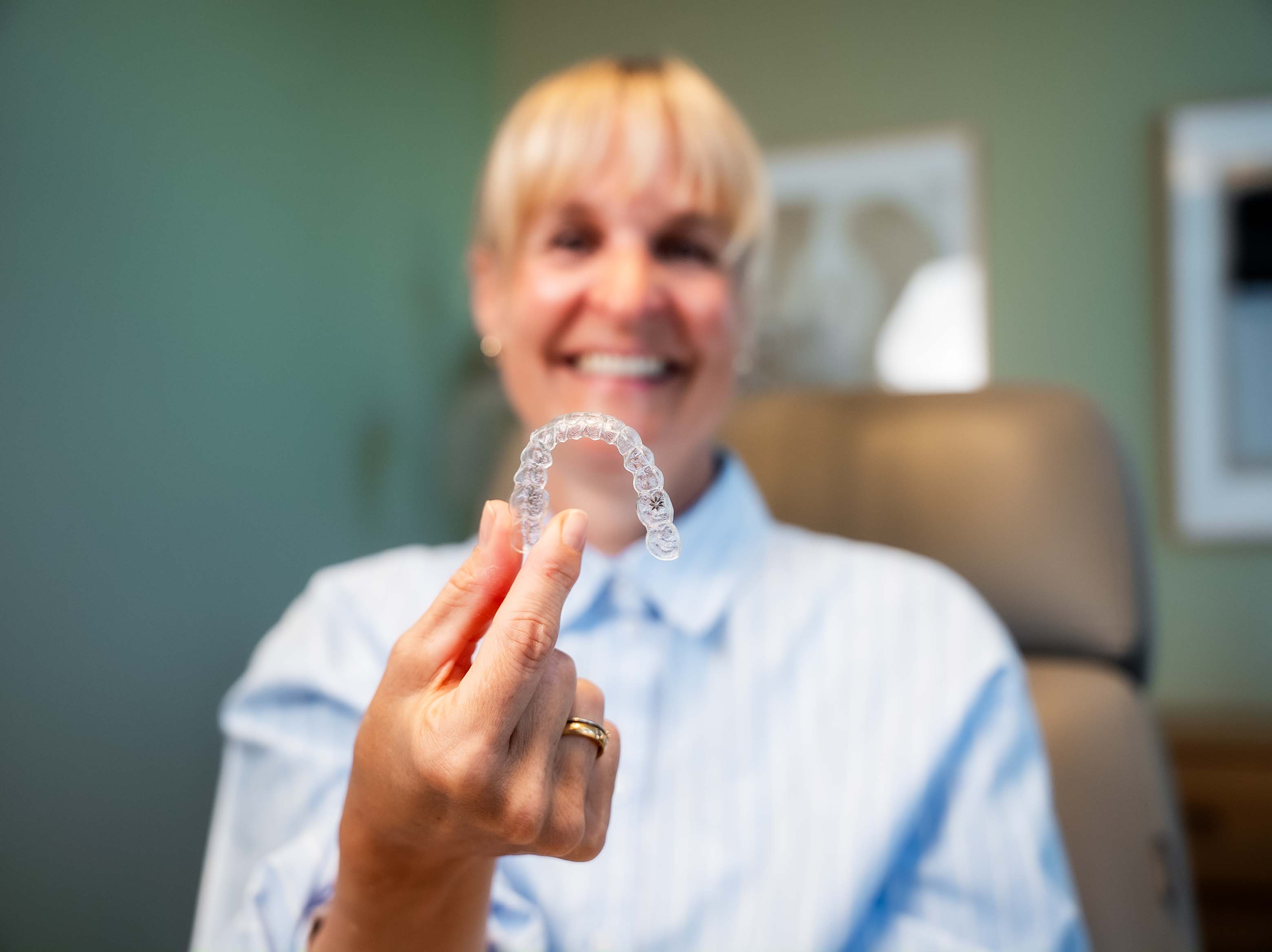 Patientin hält eine transparente Aligner-Schiene in der Hand